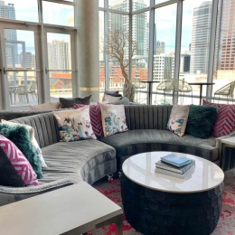 Your new community awaits a room with large windows and a circular table and couch with colorful pillow